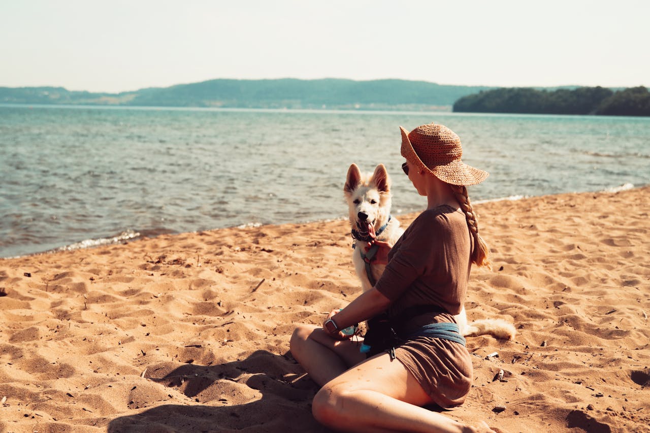 A woman sitting on the beach with her dog